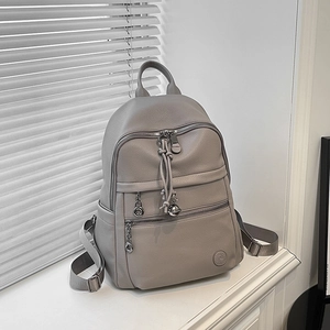 Detail of light grey lychee leather backpack showing dual zippers and silver hardware