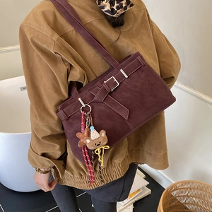 Close-up of vintage burgundy suede shoulder bag featuring a cute bear and star charm detail