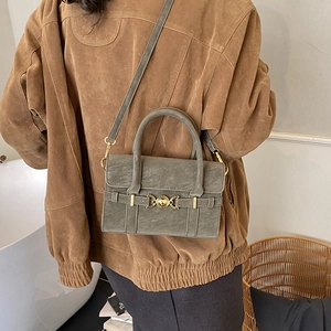 Sage green crossbody bag showing vintage matte leather and gold heart buckle detail