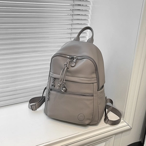 Close-up of grey litchi texture backpack featuring silver zippers and tassel drawstring