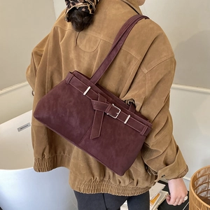 Detail of burgundy suede tote bag with decorative silver buckle on a shoulder model