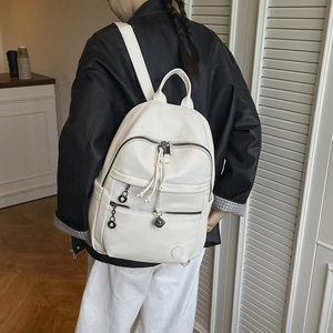 Close-up of white lychee texture backpack with zip pockets and woven knot detail