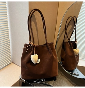 Detail of dark brown matte tote bag with plush heart charm and long shoulder strap