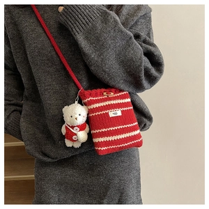 Detail of red and white striped knit bucket bag with wooden button and cute bear charm