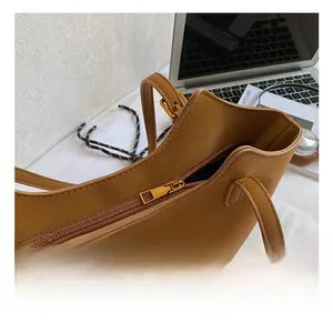Detailed close-up of a golden metal zipper on a brown pebble leather tote bag