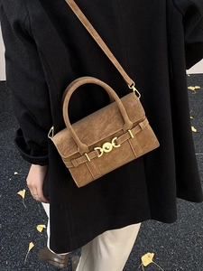 Vintage brown retro crossbody bag with gold buckle on a stylish dark winter coat