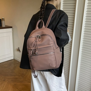 Detailed back view of pink pebbled leather backpack with drawstring and tassel on model