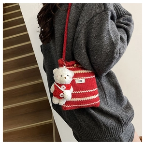 Detail of red and cream striped knitted bucket bag with a cute white teddy bear charm