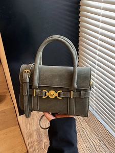 Vintage dark green crossbody bag with gold heart lock shown held by a model