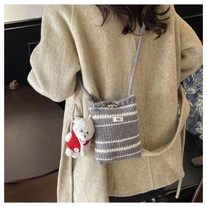 Detail of knitted bucket bag with grey stripes, wooden button, and cute bear pendant