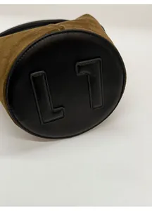 Close-up of olive green suede bucket bag featuring a reinforced black leather base