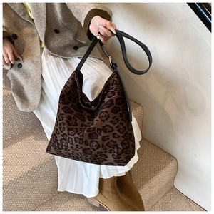 Close-up of leopard print tote bag featuring black leather strap on a model's shoulder