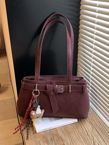 Burgundy faux suede tote bag with metal buckle and cute teddy bear charm on wood table