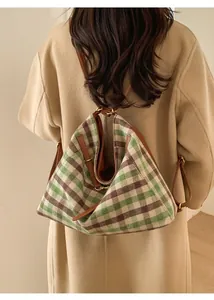 Detail of checkered shoulder bag featuring woven fabric textures and leather accents