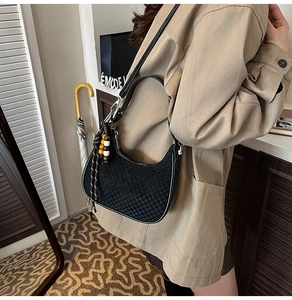Detail of black woven checkerboard texture on crescent shoulder bag with bead tassel