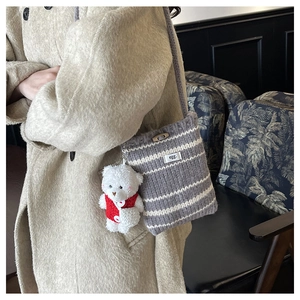 Detail of grey striped knit bucket bag with egg label and plush bear keychain