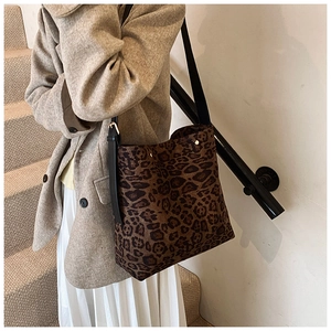 Detailed view of leopard print tote bag with black leather strap and gold hardware