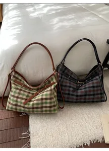 Detail view of large checkered tote bags in wool fabric with leather straps and metal buckles