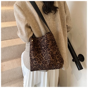 Detail view of large leopard print bucket bag with black strap on a model outfit