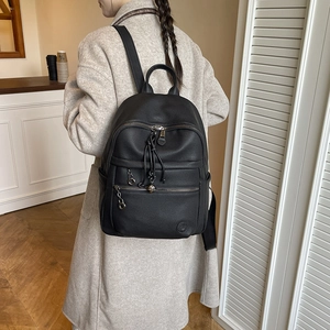 Detail of black pebbled leather backpack with metal zippers and hidden front pocket