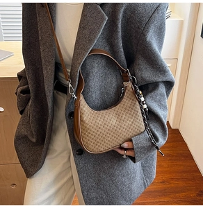 Detailed side view of brown crescent shoulder bag with elegant beaded pendant detail