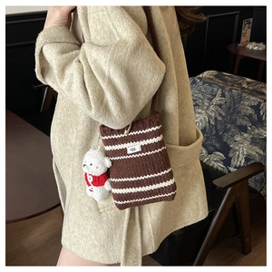 Detail of knitted crossbody bag with brown stripes and a cute plush bear charm