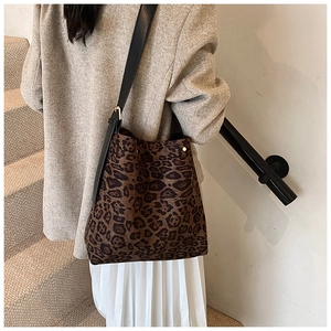 Detail of leopard print tote bag with black leather strap worn by a model in lifestyle setting