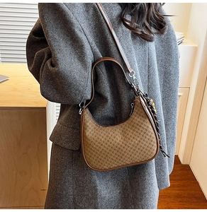 Close-up of brown crescent bag featuring woven texture and decorative side tassel detail