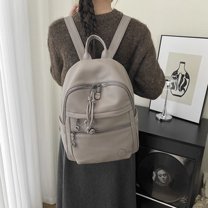 Detail of grey pebbled leather backpack with woven rope charms on double front zippers