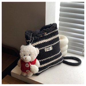 Close-up of black and white striped knit bucket bag with a cute white teddy bear charm
