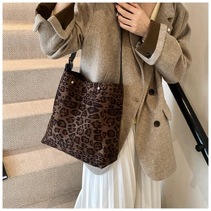 Close-up of leopard print canvas tote bag styled with blazer and pleated skirt