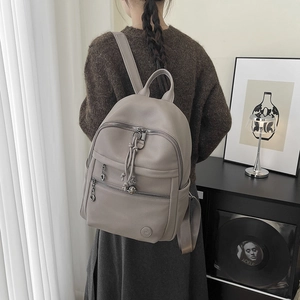 Detail of grey pebbled leather backpack with tassels on model in a cozy home setting