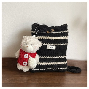 Close-up of black and white striped knit bucket bag with wooden toggle and bear charm