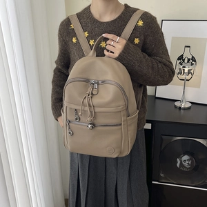 Close-up of khaki pebbled leather backpack with multi-zipper pockets and drawstring detail