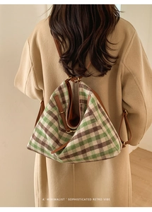Detail of green plaid drawstring backpack with leather trim and gold hardware accents