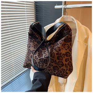 Detailed view of leopard print tote bag featuring black wide strap and golden hardware