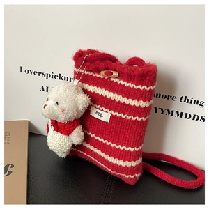 Detail of red and white striped knit bucket bag with bear charm and toggle closure