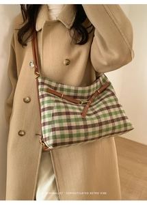 Close-up of green and brown plaid canvas tote with leather straps on a wool coat