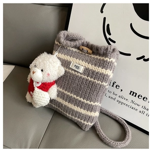 Close-up of knit bucket bag with gray stripes, wooden toggle, and cute bear charm