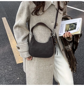Detail of dark brown crescent shoulder bag with fine textured finish on street background