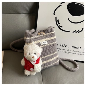 Detail of grey striped knit bucket bag featuring a small bear plush pendant accessory