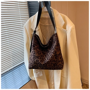 Detailed view of leopard print tote bag with black leather strap on neutral background