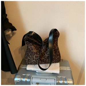 Detail of leopard print hobo bag with black leather strap on a vintage suitcase