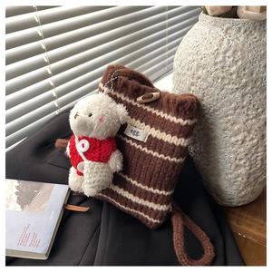 Detail of striped knit bucket bag with wooden button closure and cute bear charm