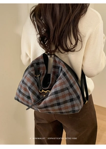 Close-up of retro plaid tote bag with black leather strap and gold metallic buckle