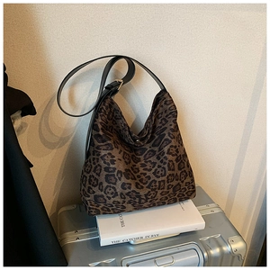 Detail of leopard print hobo bag with adjustable black strap on a vintage suitcase