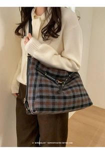 Detail of plaid tote bag featuring brown wool texture and elegant leather strap accents