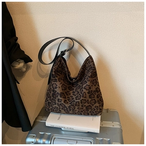 Close-up of leopard print hobo bag with black leather strap on silver suitcase