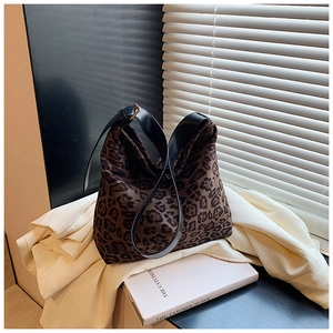 Detail of leopard print tote bag featuring wide black leather strap and metal buckle