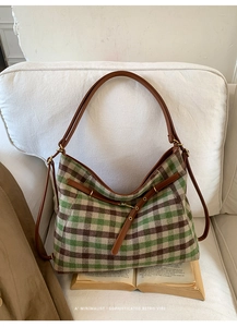 Retro plaid tote bag with brown leather straps displayed on a white sofa with books